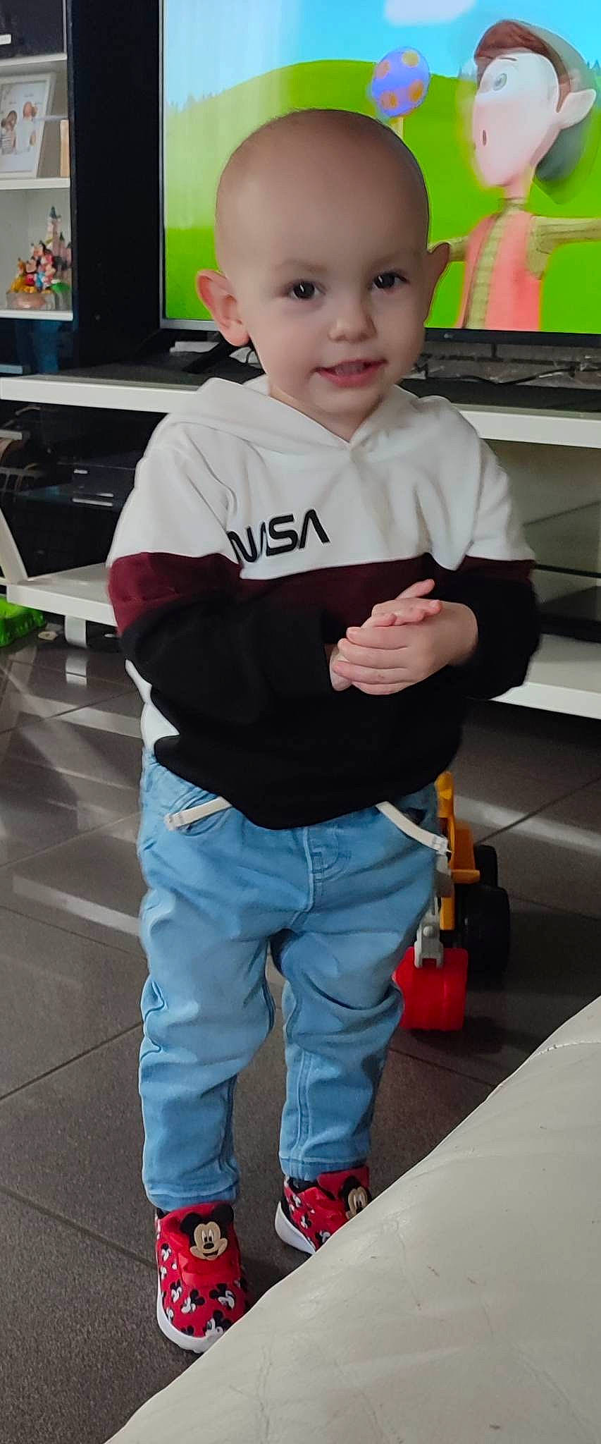 Thiago participe au concours pour gagner de l'argent avec cette photo : child, denim, electric_blue, flooring, fun, joy, led_backlit_lcd_display, person, room, shoe, sleeve, sportswear, standing, t_shirt, television, thumb, toddler, white