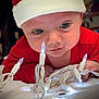 Rylin is registered to the contest to win money with this photo: baby, infant, face, eyes, christmas_lights, red_clothing, hat, holiday, indoors, curious, hands, close_up, white_lights, cute, child, toddler, festive, expression, portrait, exploration