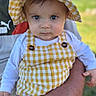 baby, blue_eyes, checkered_pattern, child, closeup, cute, fashion, grass, hand, nature, outdoor, person, portrait, summer, sun_hat, toddler, white_shirt, yellow_hat, yellow_overalls, young_child