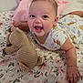 baby, infant, smiling, laughing, tummy_time, onesie, stuffed_animal, plush_toy, pacifier, bedding, blanket, floral_sheet, nursery, cute, happy, chubby_cheeks, hand, eyes, portrait, toy