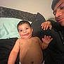 Isaias is registered to the contest to win money with this photo: baby, smiling, diaper, child, person, bed, pillow, blanket, hand, face, skin, cheeks, young_person, indoor, candid, family, comfort, relaxation, happy, portrait
