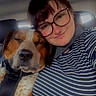 Beau is registered to the contest to win money with this photo: dog, person, selfie, car, passenger_seat, snuggling, sleepy, face, glasses, striped_shirt, seatbelt, collar, brown_and_white, close_up, indoors, vehicle, pet, human, companionship, portrait