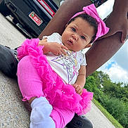 Jeylani joined the competition — help win amazing prizes! baby, child, pink_clothing, headband, socks, concrete, outdoor, car, legs, adult, greenery, sky, clouds, curious_expression, sitting, footwear, protective, daylight, casual, cute