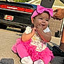 Jeylani is registered to the contest to win money with this photo: baby, child, pink_bow, pink_leggings, pink_skirt, white_socks, tshirt, car, driveway, house, adult_hand, sunlight, outdoor, smiling, cute, portrait, person, footwear, tattoo, black_sandal