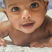 Ayaan is registered to the contest to win money with this photo: baby, infant, close_up, face, eyes, skin, hair, expression, curious, lying_down, cushion, pattern, stars, animal_drawing, child, indoors, cute, portrait, tummy_time, young