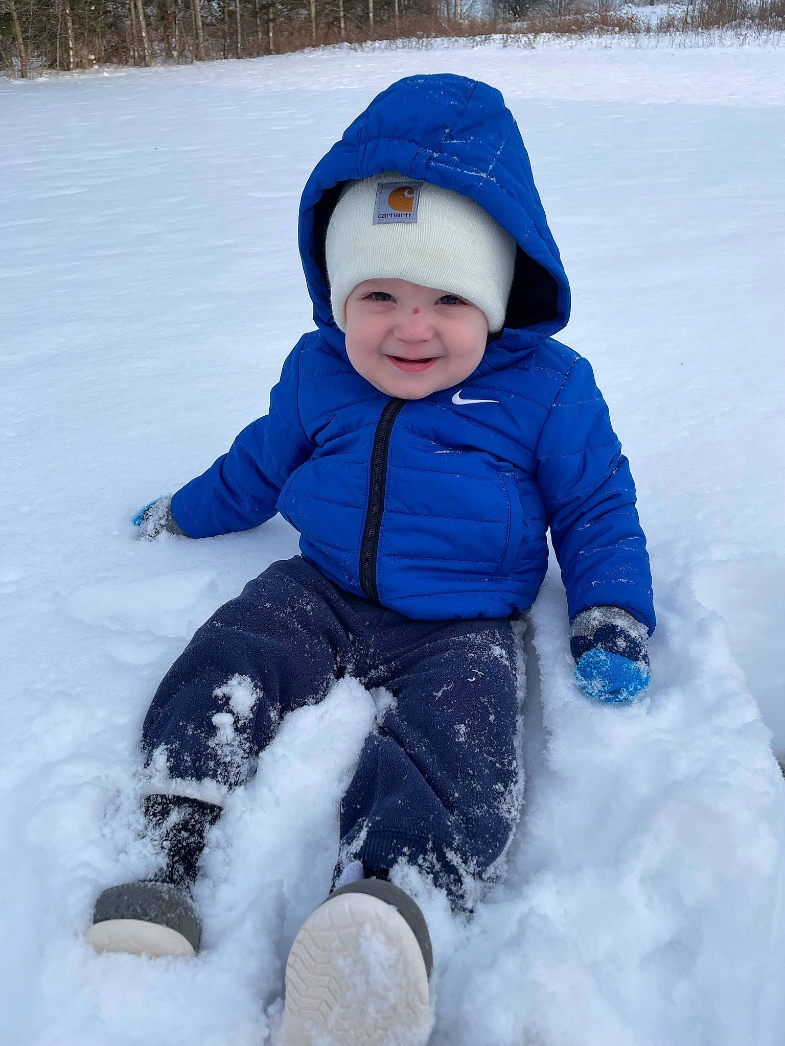 Koa is registered to the contest to win money with this photo: baby_toddler_clothing, cap, child, electric_blue, face, freezing, glove, happy, headwear, jacket, joy, people_in_nature, person, play, recreation, sitting, sleeve, smile, snow, toddler
