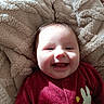 baby, blanket, bunny_print, child, closeup, comfort, cozy, cute, face, happy, indoors, infant, light_shadow, portrait, red_onesie, sleepwear, smiling, soft_texture, warm, wooden_toy