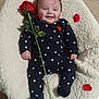 baby, infant, smiling, onesie, heart_pattern, rose, rose_petals, face_paint, fluffy_cushion, wooden_floor, cute, happy, lying_down, indoor, soft_texture, red, black_clothing, cheeks, head, person