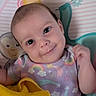baby, infant, child, smile, face, onesie, rainbow, stars, yellow_cloth, patterned_background, cute, lying_down, bright_eyes, pastel_colors, happy, indoor, soft_lighting, closeup, portrait, adorable