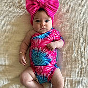 Haddie joined the competition — help win amazing prizes! baby, infant, child, pink_bow, tie_dye, onesie, blanket, laying_down, wide_eyes, cute, headband, portrait, indoors, skin, person, one_person, baby_clothing, soft_texture, colorful, adorable