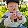 black_cap, blue_sky, cap, child, cute, flower, grass, greenery, hands, jeans, nature, outdoor, portrait, sitting, striped_sweater, sunlight, sweater, toddler, tree, yellow_flower