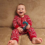 Alessio a rejoint le concours — aidez-le/la à gagner de superbes lots ! baby, beige, candy_cane, child, couch, cozy, cute, face, feet, happy, holiday, indoors, infant, pajamas, portrait, red_clothing, sitting, smiling, toy, young_child