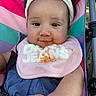 baby, child, stroller, headband, bib, food_stain, smile, face, arm, clothing, colorful, outdoor, seatbelt, cute, messy, person, portrait, closeup, infant, happy