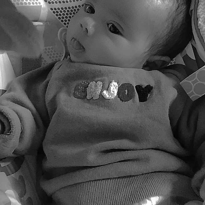 Zaïn participe au concours pour gagner de l'argent avec cette photo : baby, black_and_white, blanket, child, clothing, cozy, cute, expression, face, head, indoors, infant, lying_down, patterned_blanket, person, portrait, soft_toys, sweater, text_on_clothing, tongue_out