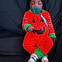 baby, infant, pacifier, pumpkin_costume, halloween, sleeping, beanie, socks, striped_sleeves, green_trim, onesie, black_blanket, cozy, closed_eyes, pacifier_clip, crossed_legs, cute, resting, soft_fabric, portrait