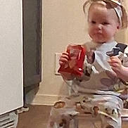 Nataila joined the competition — help win amazing prizes! toddler, child, pajamas, headband, bow, snack, food_package, chair, indoor, floor, kitchen, cabinet, wall, curious, sitting, person, young_child, casual, home, cozy