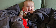 Aurora joined the competition — help win amazing prizes! baby, blanket, couch, plush_toy, smile, child, indoor, green_couch, gray_blanket, happy, portrait, infant, cozy, cute, person, furniture, home, comfort, young_child, soft_toys