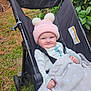 baby, black_stroller, blanket, child, cozy, cute, face, grass, greenery, happy, infant, nature, outdoor, pajamas, person, pink_hat, pom_poms, portrait, smile, stroller