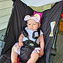 baby, child, stroller, headband, bow, straps, outdoor, footwear, pink, black, white, infant, cute, expression, sitting, clothing, person, face, legs, feet