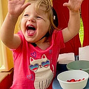 Everly is registered to the contest to win money with this photo: toddler, child, smiling, happy, pink_shirt, cat_graphic, shorts, indoor_playhouse, table, bowls, strawberries, raising_hands, cute, playful, blond_hair, casual_clothing, fun, joyful, portrait, daylight