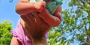 Stella is registered to the contest to win money with this photo: baby, child, arm, hand, greenery, trees, sky, blue_sky, outdoor, sunlight, headwear, bow, smiling, cute, person, infant, nature, summer, happy, portrait