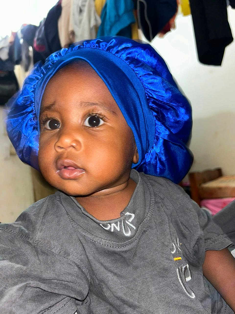 Erwyn participe au concours pour gagner de l'argent avec cette photo : baby, background, blue_bonnet, casual, child, clothes, clothing, curious, cute, expression, eyes, face, grey_shirt, headwear, indoor, indoors, person, portrait, toddler, young_child