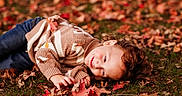 Rhettlee is registered to the contest to win money with this photo: child, smiling, autumn, leaves, grass, sweater, jeans, outdoor, fall, nature, happy, cute, playing, seasonal, portrait, casual, warm, relaxed, curly_hair, daylight
