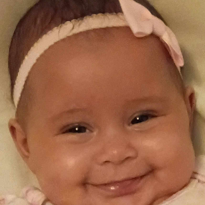 Princesa is registered to the contest to win money with this photo: baby, infant, child, smiling, portrait, close_up, headband, bow, facial_expression, face, eyes, cheeks, bibs, baby_clothing, pastel, floral_pattern, indoors, soft_lighting, happy, photography