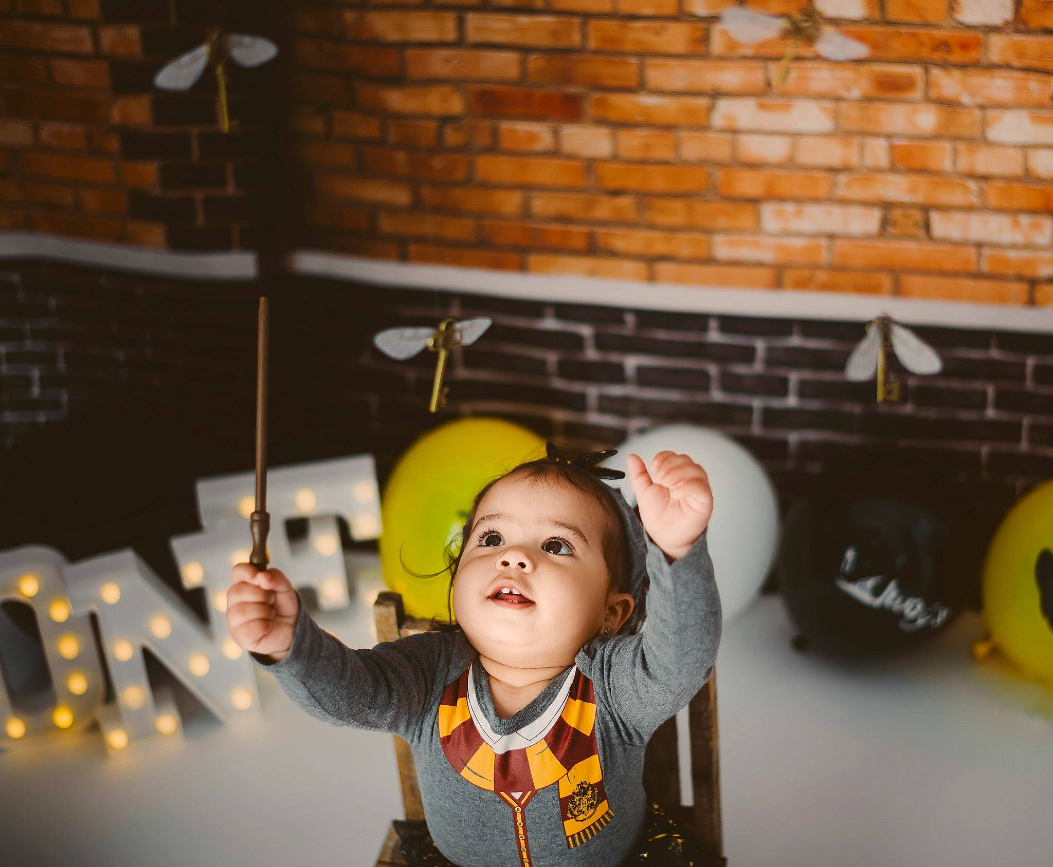 Charlie is registered to the contest to win money with this photo: automotive_tire, baby, brick, brickwork, child, flash_photography, fun, happy, helmet, leisure, person, personal_protective_equipment, play, recreation, room, sitting, smile, t_shirt, toddler, wood