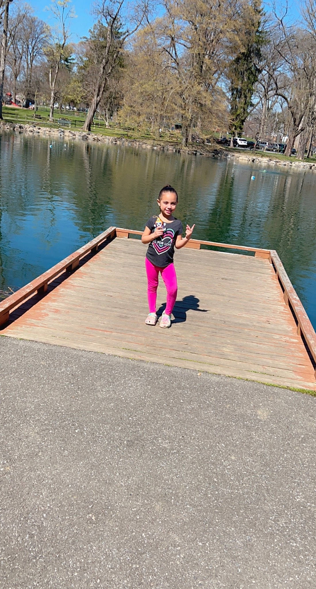 Leiana is registered to the contest to win money with this photo: asphalt, fun, grass, joy, lake, leisure, magenta, pedestrian, people_in_nature, person, plant, recreation, reservoir, shorts, sitting, toddler, tourism, travel, tree, vacation