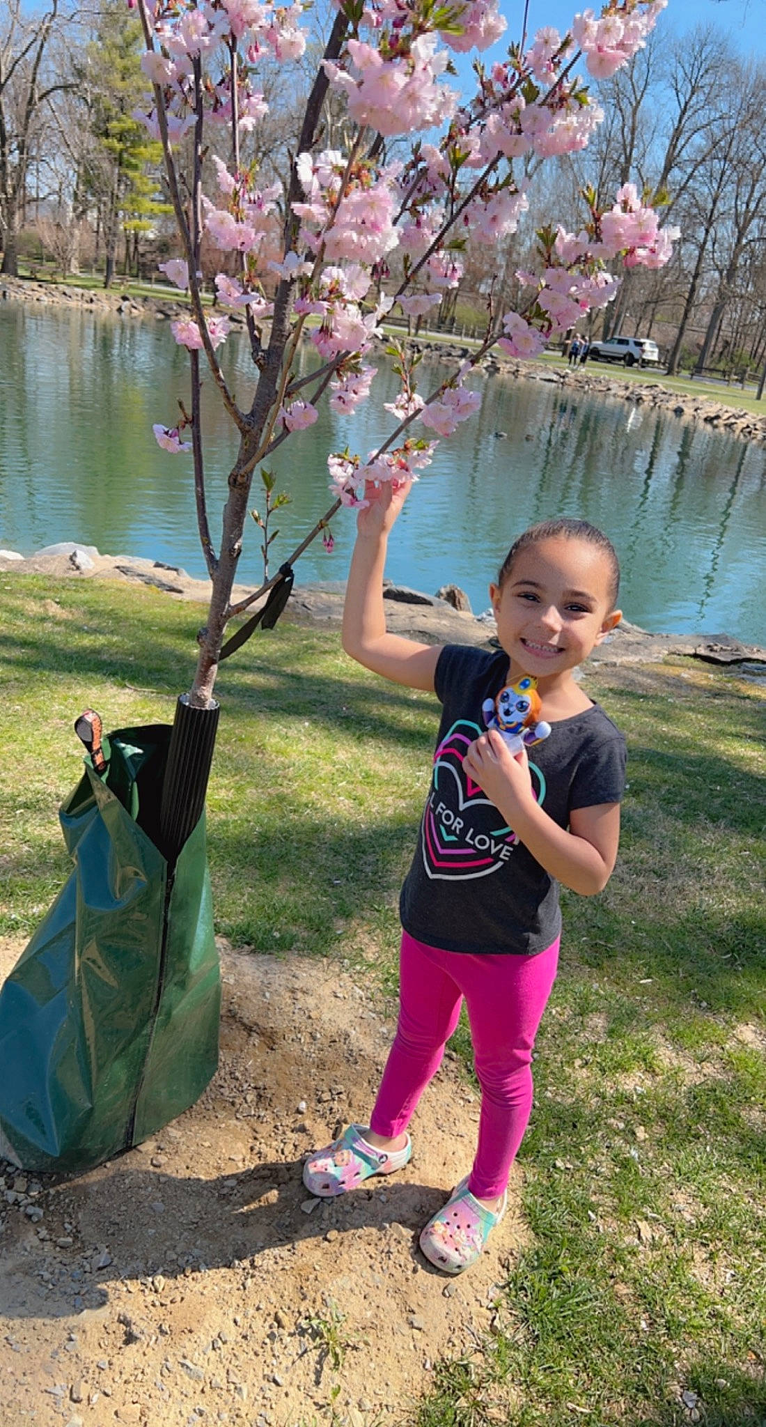 Leiana is registered to the contest to win money with this photo: blossom, botany, branch, child, flower, fun, grass, happy, joy, lake, leisure, people_in_nature, person, pink, plant, recreation, sandal, spring, toddler, tree