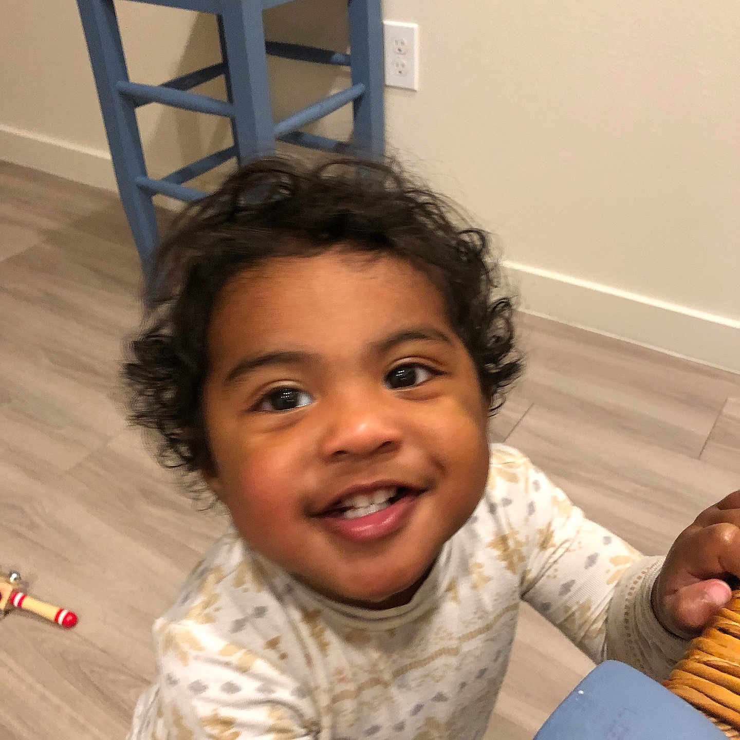 Celine is registered to the contest to win money with this photo: blue_chair, bright_eyes, casual_clothing, chair, child, curly_hair, cute, flooring, furniture, happy, holding, home, indoor, person, playful, portrait, smiling, toddler, wooden_floor, young_child