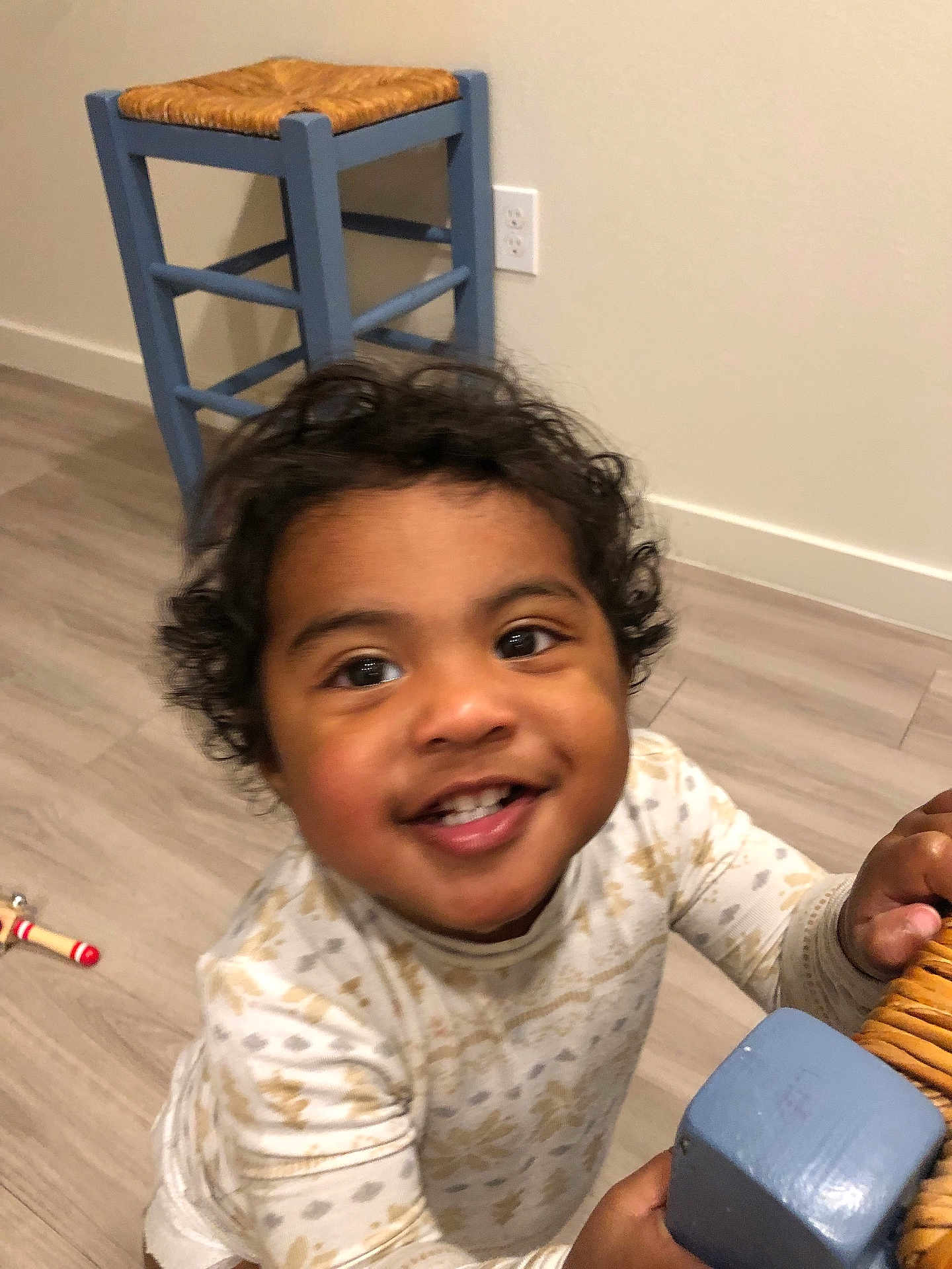 Celine is registered to the contest to win money with this photo: blue_chair, bright_eyes, casual_clothing, chair, child, curly_hair, cute, flooring, furniture, happy, holding, home, indoor, person, playful, portrait, smiling, toddler, wooden_floor, young_child