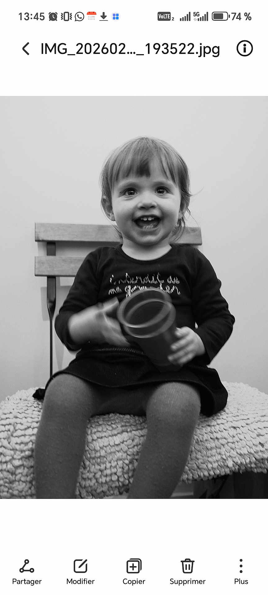 Loxane a rejoint le concours — aidez-le/la à gagner de superbes lots ! child, toddler, smiling, black_and_white, bench, wooden_bench, cup, toy, portrait, sitting, happy, clothing, dress, tights, chair, cushion, indoor, screenshot_ui, grin, playful