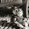 child, children, sibling, baby, blanket, car, vintage_car, black_and_white, portrait, outdoor, grass, toddler, smile, headband, clothing, shoes, cute, family, hug, happy