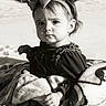 Tessa is registered to the contest to win money with this photo: toddler, child, baby, blanket, headband, bow, velvet_dress, outdoor, snow, sand, portrait, black_and_white, serious_expression, cute, small_hand, sitting, soft_texture, young_child, face, clothing