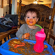 Tessa joined the competition — help win amazing prizes! toddler, child, messy, food, high_chair, sippy_cup, smiling, face_paint, hands, wooden_chair, indoor, home, plate, feeding, baby, tableware, pink, blue, playful, happy