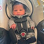 Delijah is registered to the contest to win money with this photo: baby, child, car_seat, hoodie, gray_clothing, black_socks, straps, infant, seatbelt, indoor, person, cute, young, seat, safety, hands, face, head, expression, closeup