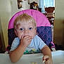 toddler, child, high_chair, snack, blue_eyes, blond_hair, indoor, furniture, curtain, table, hand, face, person, clothing, seat, home, eating, cute, portrait, young_child