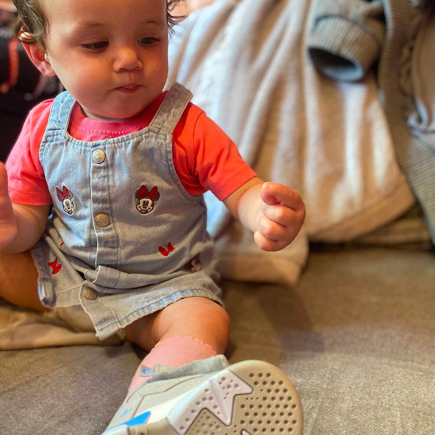 Ezmae-Faith joined the competition — help win amazing prizes! baby, blue, casual, child, clothing, couch, curious, denim, face, footwear, hand, indoor, minnie_mouse, overall, person, pink, portrait, sneaker, sock, toddler