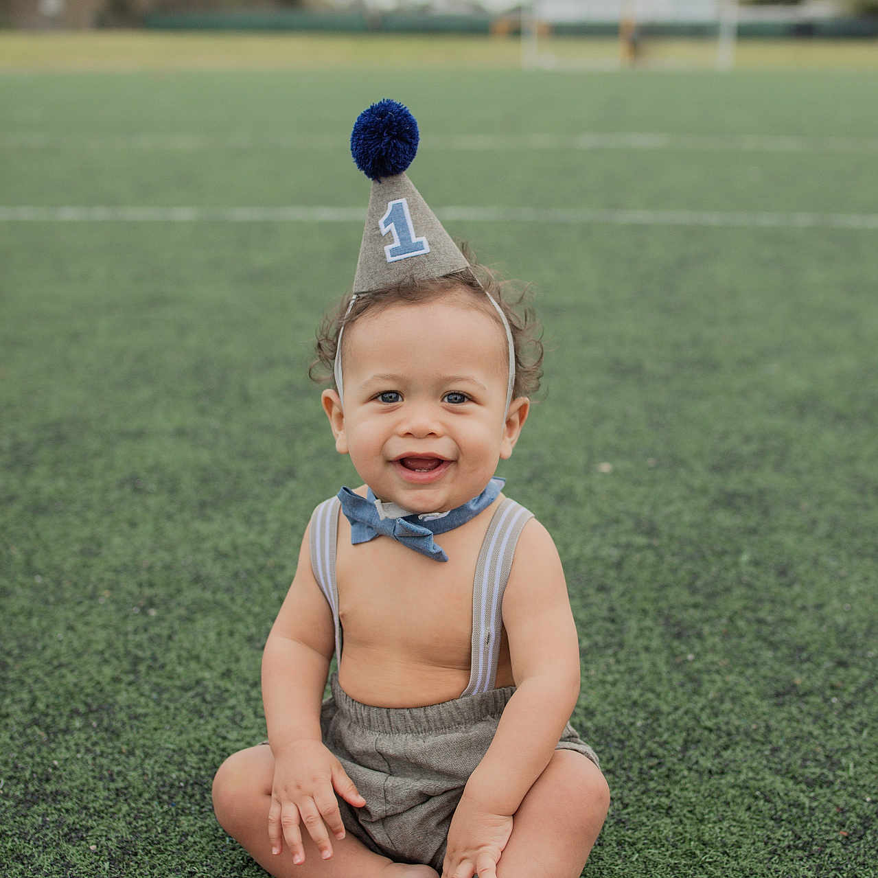 Kamden is registered to the contest to win money with this photo: accessories, baby, bodypart, clothing, face, finger, formalwear, grass, hand, happy, hat, head, partyhat, people, person, photography, plant, portrait, sitting, tie