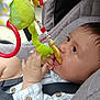 baby, child, toy, plush_toy, stroller, seatbelt, gray_cushion, hand, face, profile, clothing, button, curious, chewing, indoor, closeup, infant, cute, young_child, sitting