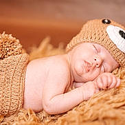 Ilyano a rejoint le concours — aidez-le/la à gagner de superbes lots ! baby, newborn, sleeping, knit_hat, pompom, blanket, fur_blanket, cozy, infant, portrait, soft_lighting, cute, peaceful, hand, face, closed_eyes, skin, studio_photo, warm_tones, props