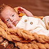 baby, basket, blanket, bokeh, buttons, closeup, cozy, infant, knitted_throw, neutral_background, newborn, onesie, portrait, props, sleepy, soft_texture, studio_lighting, tiny_feet, tiny_hand, wooden_logs