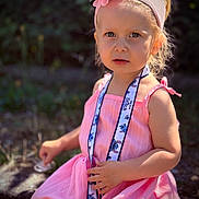 Lindsay a rejoint le concours — aidez-le/la à gagner de superbes lots ! accessory, blonde_hair, child, curious_expression, cute, daylight, fashion, flower, girl, headband, lanyard, nature, outdoor, pink_dress, portrait, sitting, stitch, summer, sunlight, young_child