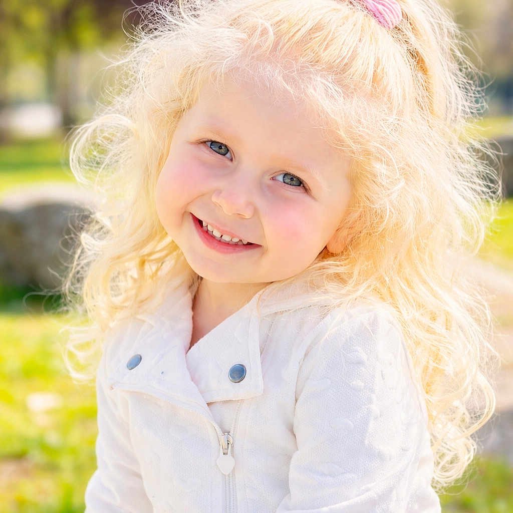 Lindsay Sabrina a rejoint le concours — aidez-le/la à gagner de superbes lots ! child, girl, smiling, blonde_hair, curly_hair, pink_bow, white_jacket, outdoor, park, sunlight, portrait, happy, face, blue_eyes, nature, grass, tree, daylight, cute, person