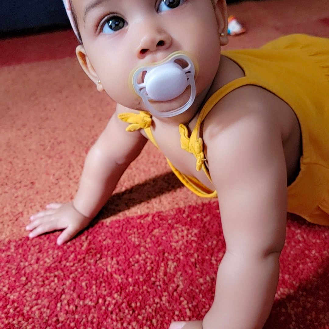 Léa participe au concours pour gagner de l'argent avec cette photo : baby, carpet, child, closeup, crawling, curious, cute, earrings, eyes, face, flower, hand, headband, indoor, infant, pacifier, portrait, skin, yellow_outfit, young_child