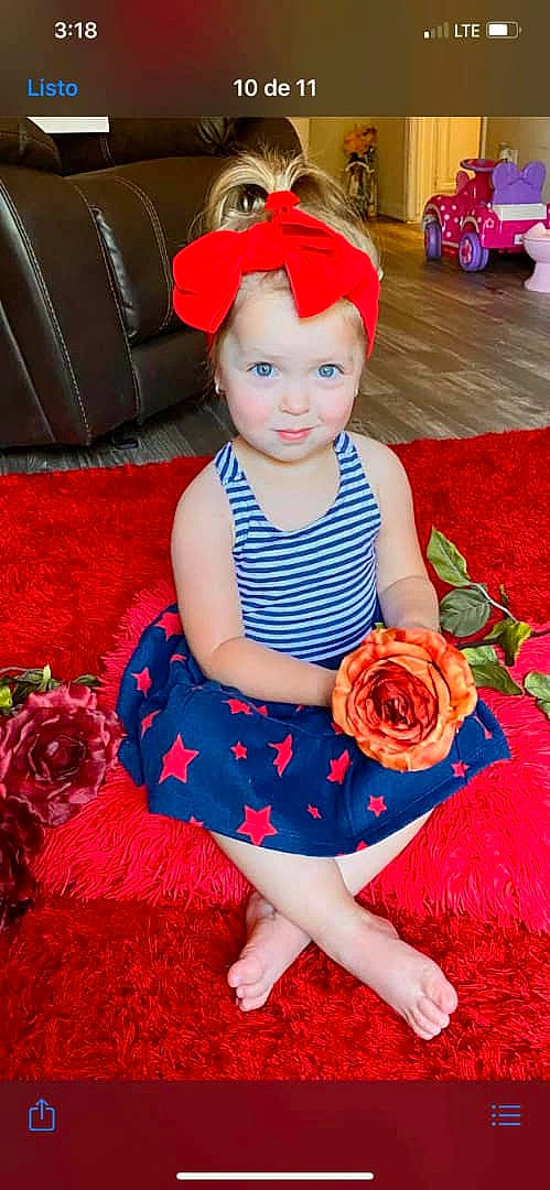 Briana is registered to the contest to win money with this photo: baby, baby_toddler_clothing, child, child_model, clothing, costume, costume_accessory, dress, hair_accessory, headband, headgear, headwear, pattern, person, petal, plant, red, sitting, smile, toddler