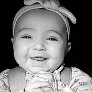 Millie is registered to the contest to win money with this photo: baby, smiling, headband, infant, hands, clothing, cute, face, portrait, child, young, happy, closeup, black_and_white, expression, adorable, person, background, pattern, sleeves