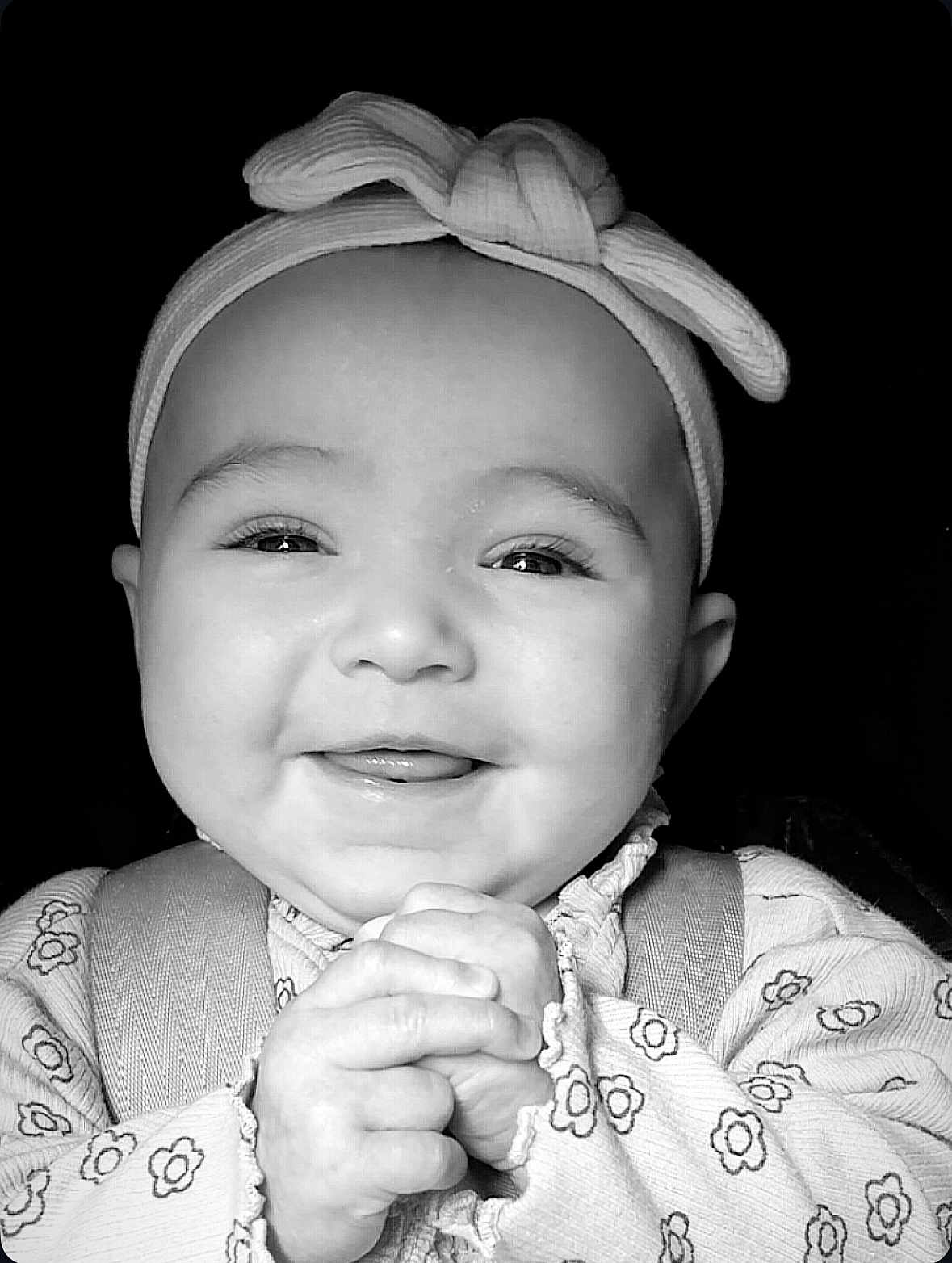 Millie is registered to the contest to win money with this photo: baby, smiling, headband, infant, hands, clothing, cute, face, portrait, child, young, happy, closeup, black_and_white, expression, adorable, person, background, pattern, sleeves